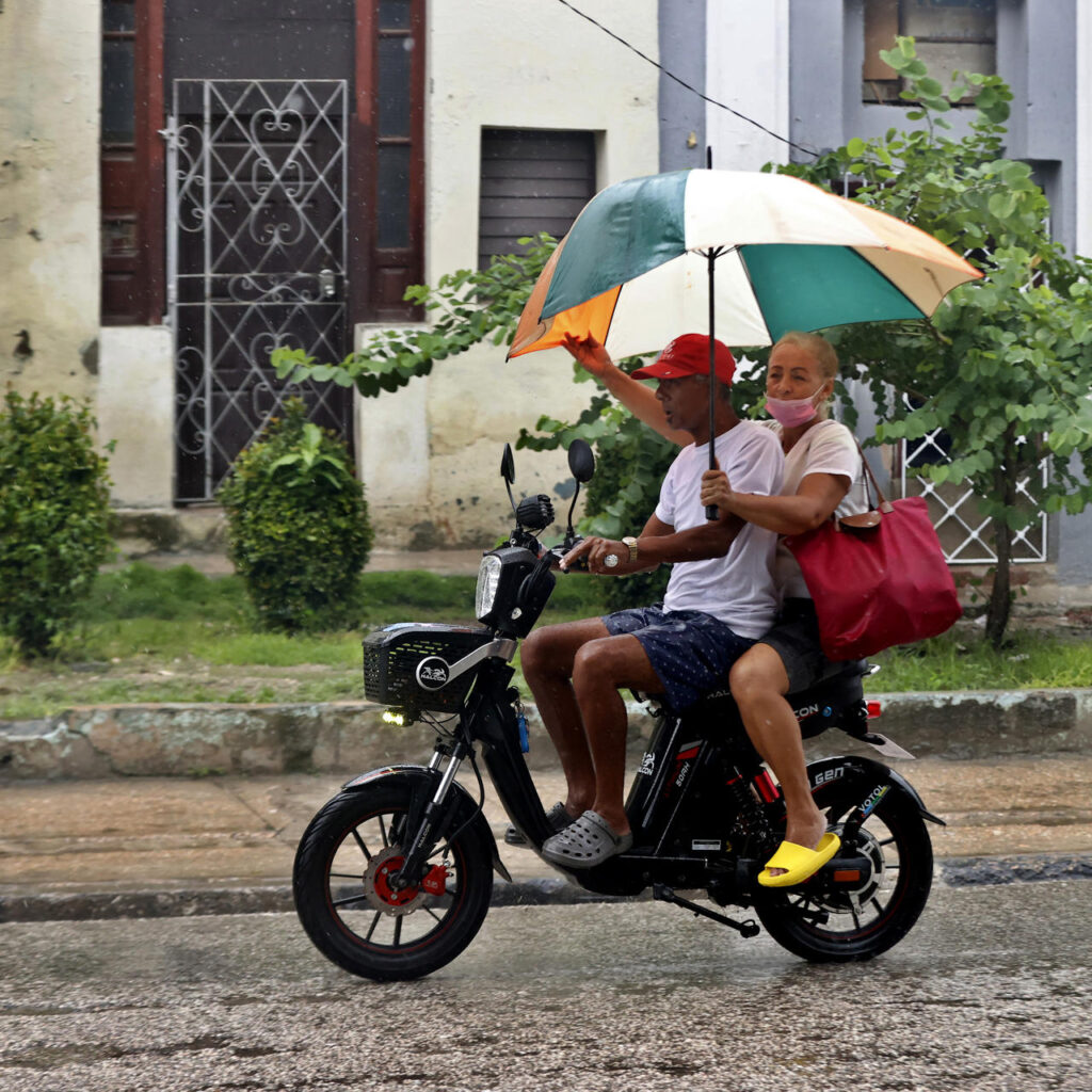 dos personas en moto y paraguas por el huracán melissa